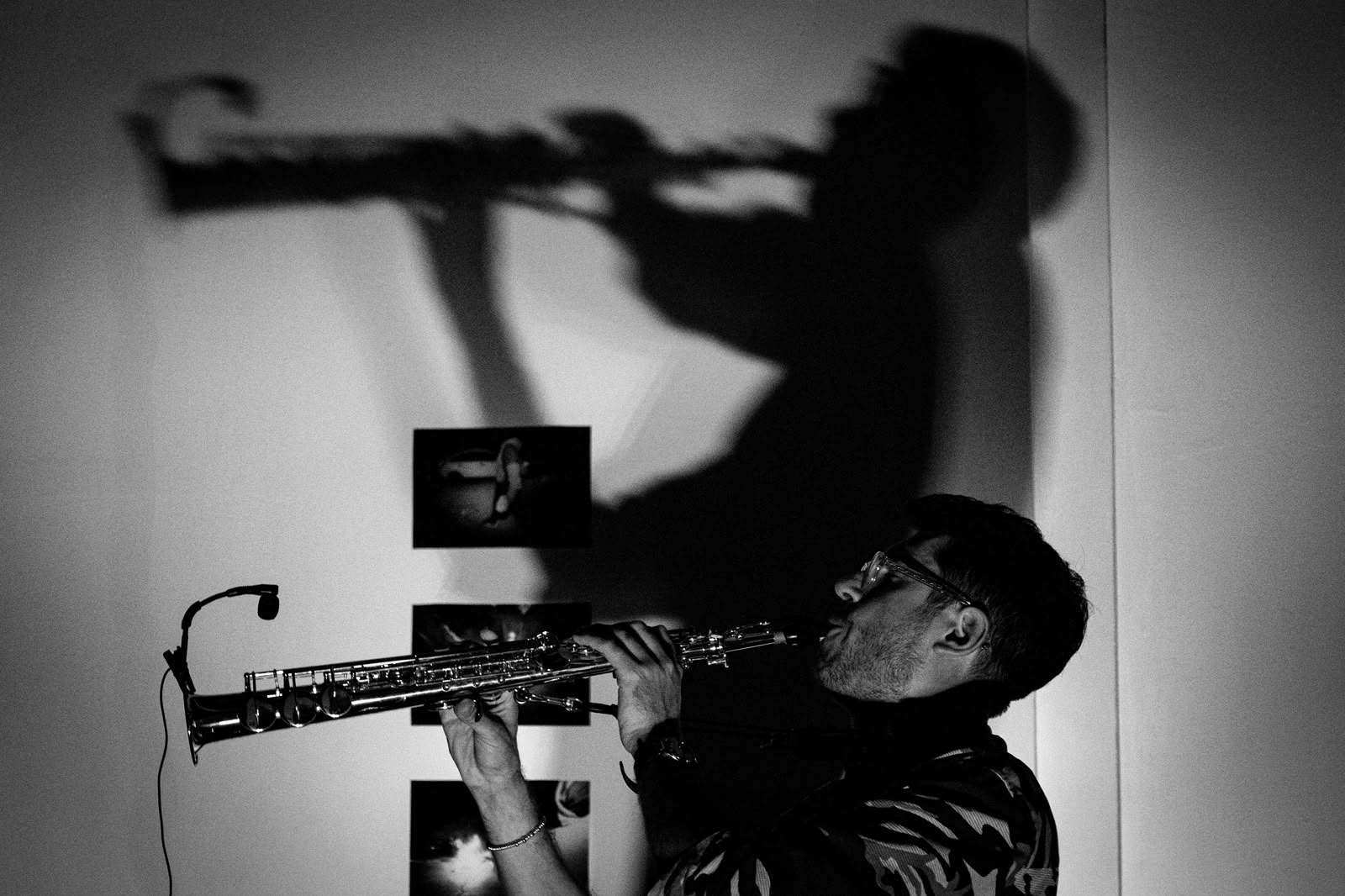 Saxophonist Alberto Cavallaro performing, with his shadow and instrument projected on the wall behind him.