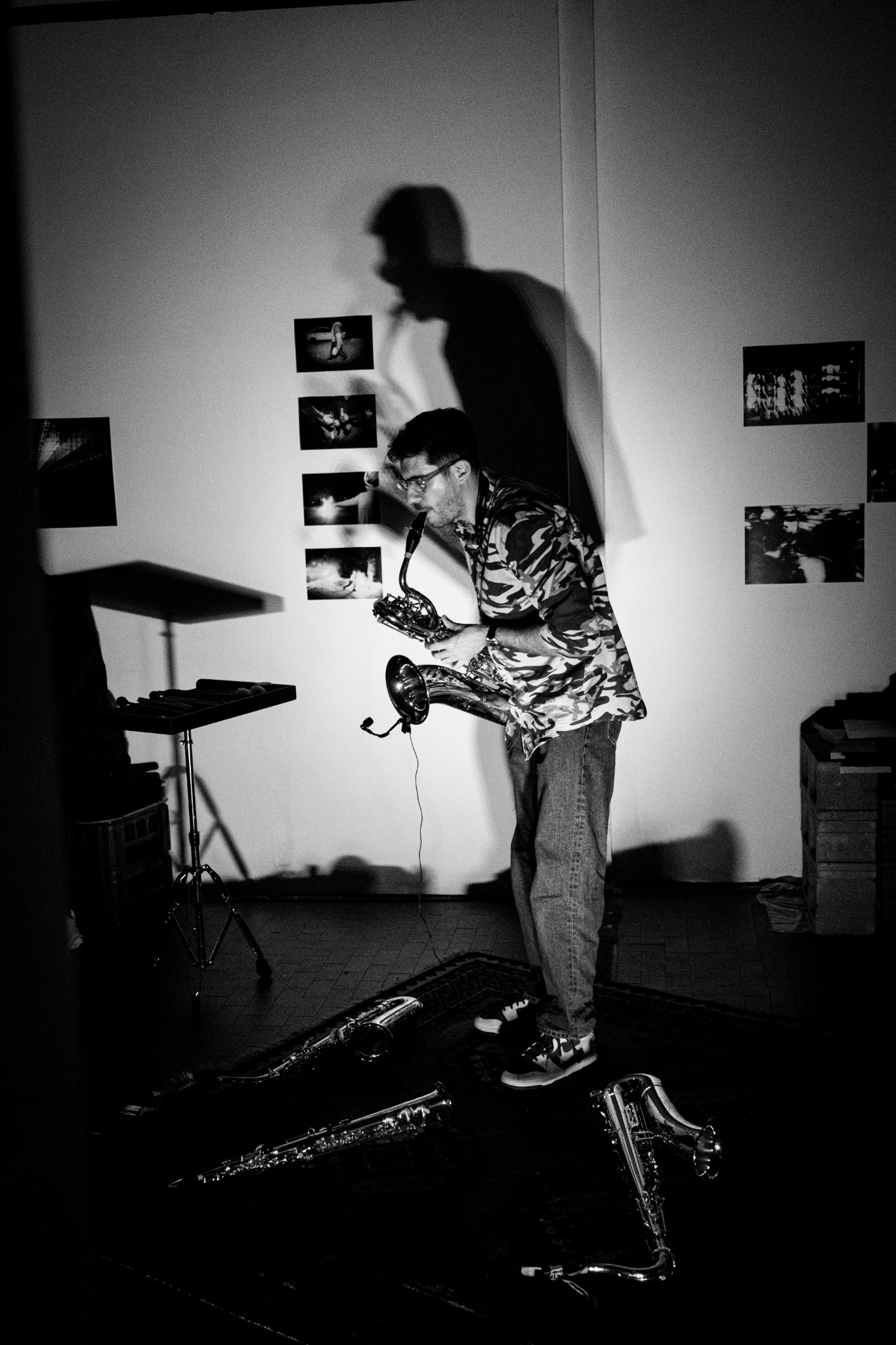 Black-and-white photograph of Alberto Cavallaro playing saxophone at Musica Randagia, with his shadow on the wall.